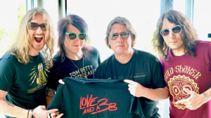 Wayne posing with Love and a .38 band members and holding up a band t-shirt